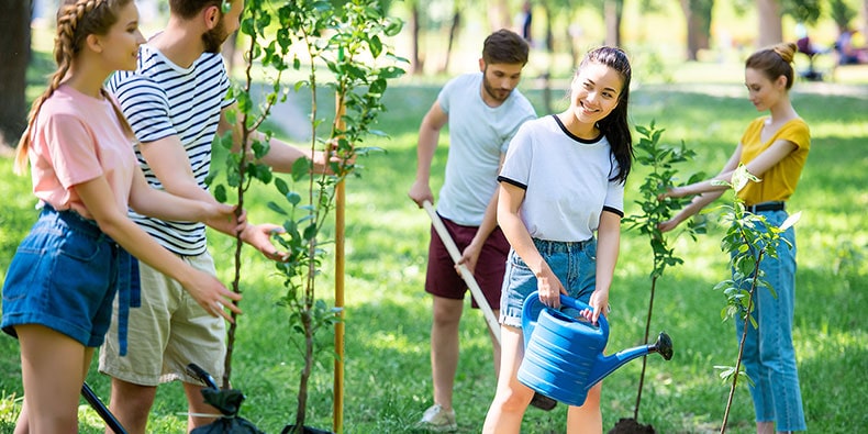 a group of young adults planting and watering trees